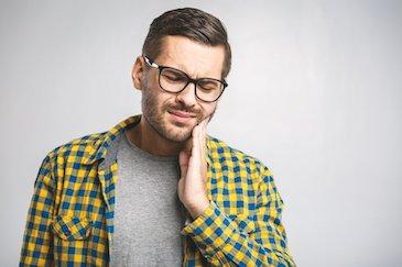 man holding his jaw from tooth pain during a dental emergency